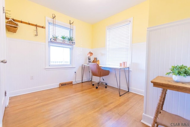 home office featuring visible vents, wainscoting, and light wood finished floors
