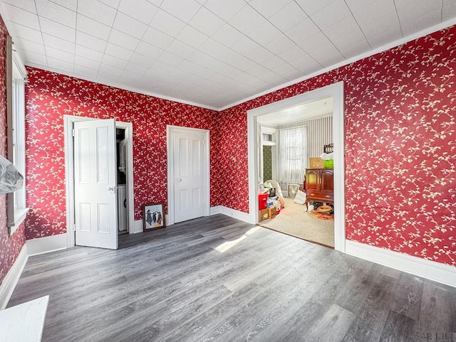 521 N Julian St, Ebensburg, PA 15931 - empty room with wood finished floors, ornamental molding, wallpapered walls, and a wood stove