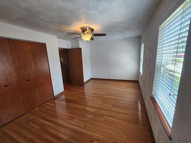 unfurnished bedroom with multiple windows, hardwood / wood-style floors, and ceiling fan