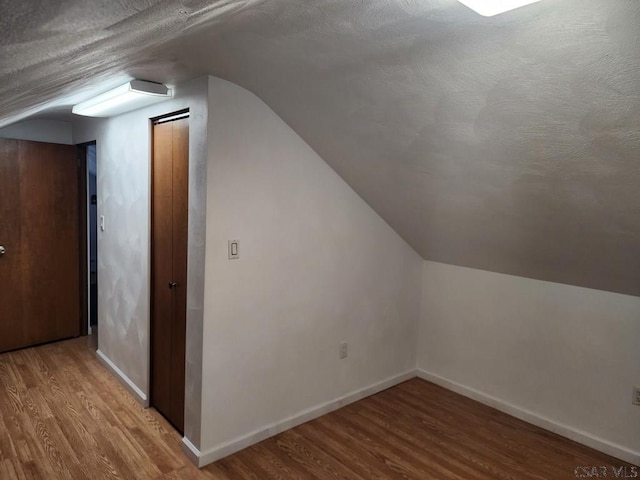 bonus room featuring hardwood / wood-style flooring, vaulted ceiling, and a textured ceiling