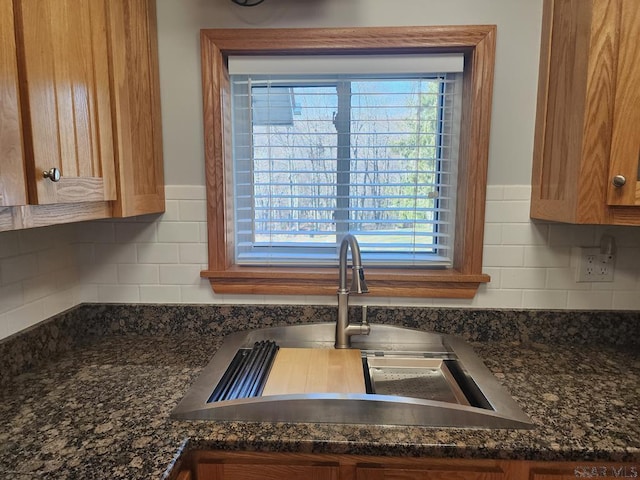 details featuring sink, backsplash, and dark stone counters