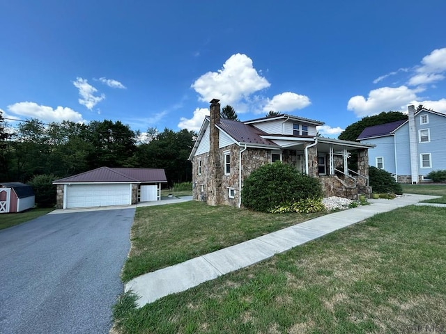 view of front of property featuring a garage, an outdoor structure, a front lawn, and covered porch