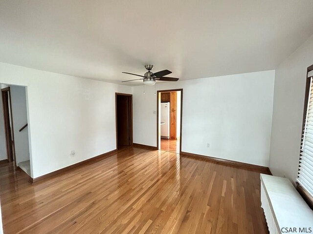 unfurnished bedroom with white refrigerator, ceiling fan, and light wood-type flooring