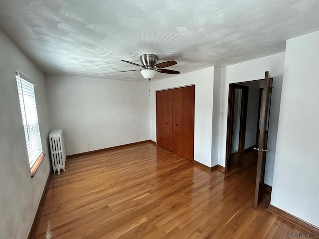 empty room featuring radiator, hardwood / wood-style flooring, and ceiling fan