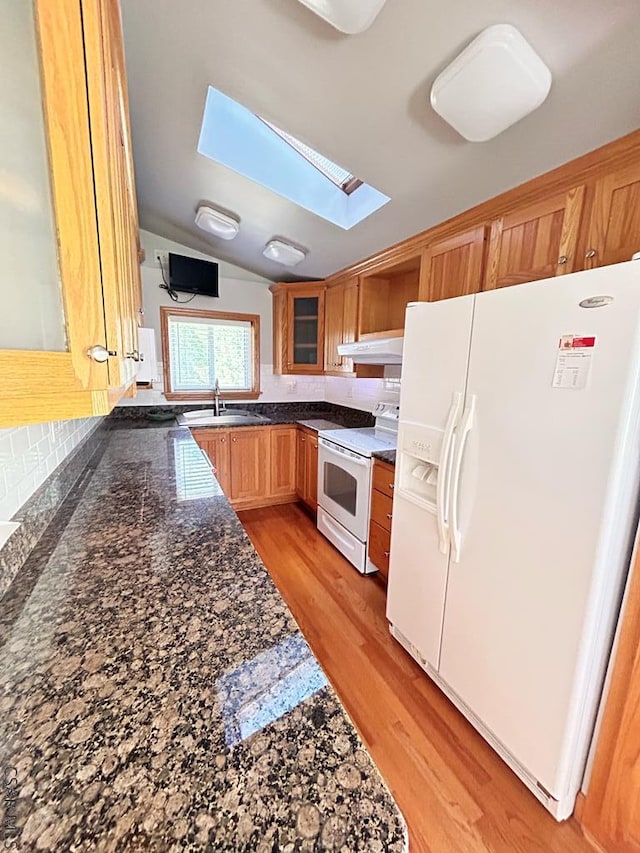 kitchen featuring lofted ceiling with skylight, sink, light wood-type flooring, decorative backsplash, and white appliances