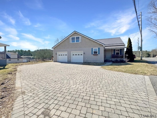 view of front of home featuring a front lawn, decorative driveway, covered porch, and metal roof