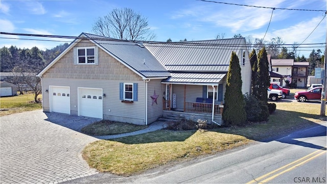 view of front of house with a standing seam roof, a front yard, covered porch, and metal roof