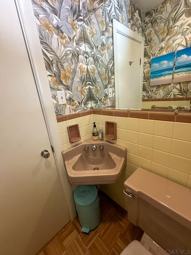 bathroom featuring tile walls, parquet floors, sink, and toilet