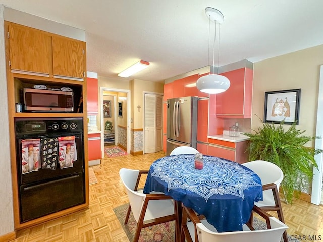 kitchen featuring decorative light fixtures, light parquet flooring, and appliances with stainless steel finishes