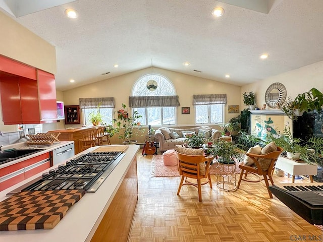 kitchen with lofted ceiling, sink, a textured ceiling, appliances with stainless steel finishes, and light parquet flooring