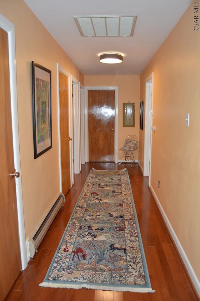 corridor with a baseboard radiator and dark hardwood / wood-style floors