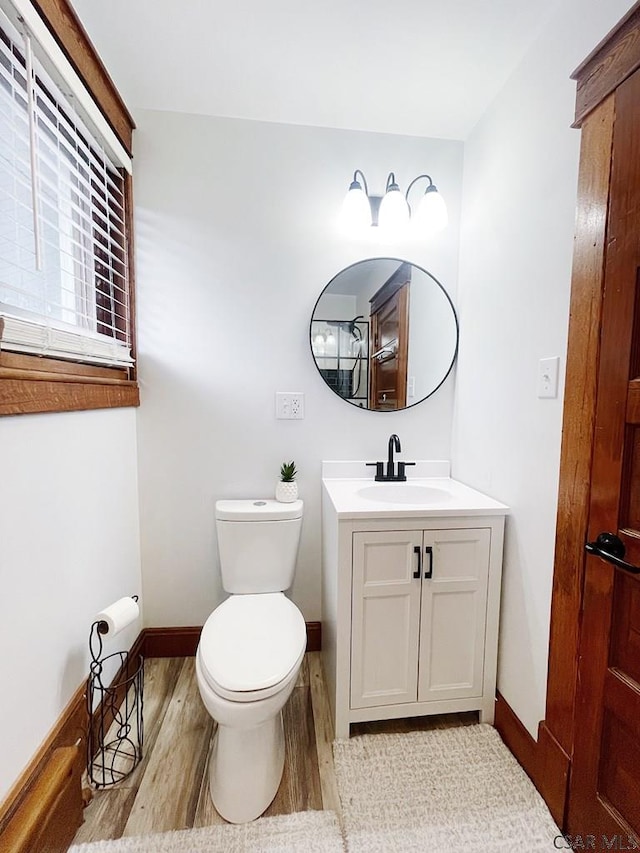 bathroom featuring wood-type flooring, toilet, and vanity