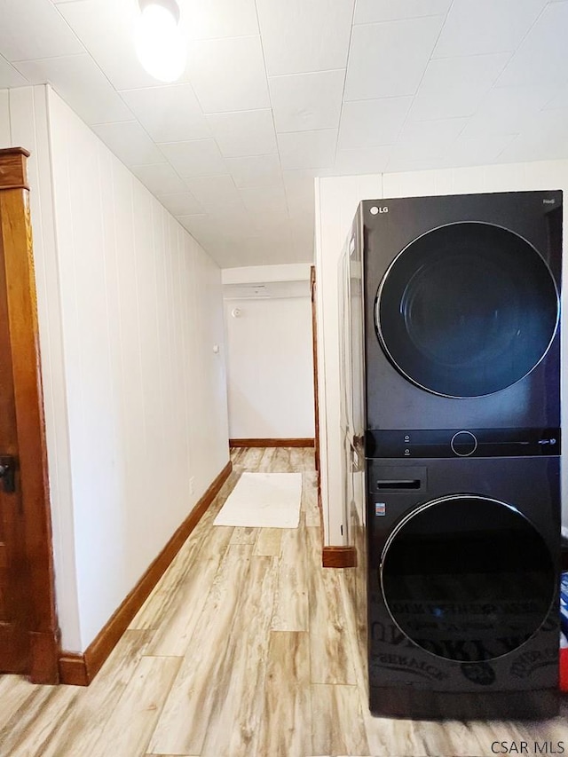 laundry area with stacked washer / drying machine and wood-type flooring