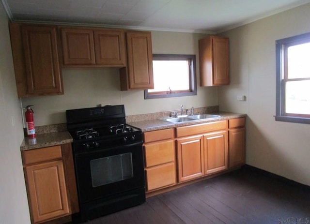 kitchen with black range with gas cooktop, sink, crown molding, and dark wood-type flooring