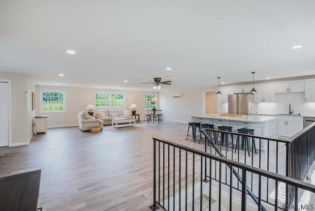 living room with sink, light hardwood / wood-style floors, and ceiling fan