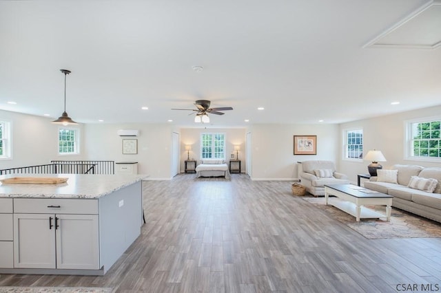 unfurnished living room featuring a wealth of natural light, an AC wall unit, and light wood-type flooring