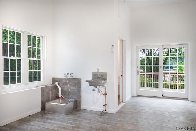 interior space with sink, light hardwood / wood-style floors, and a high ceiling