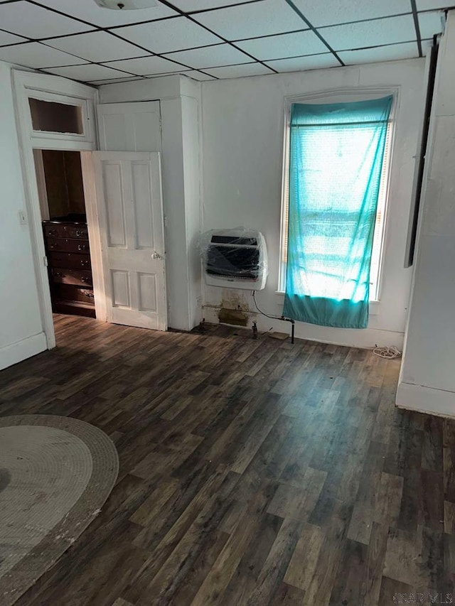 interior space with a drop ceiling, dark wood finished floors, and heating unit