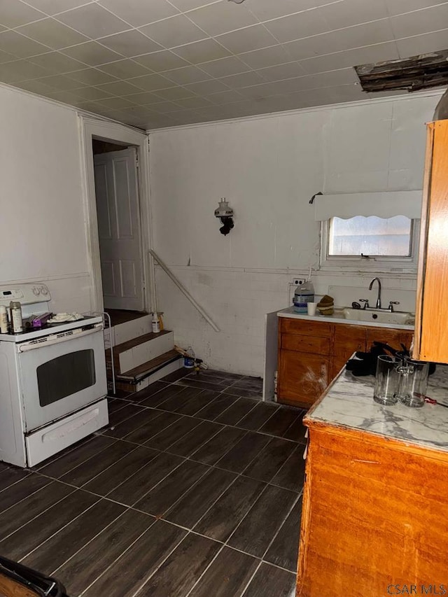 kitchen featuring brown cabinets, light countertops, white electric stove, and a sink