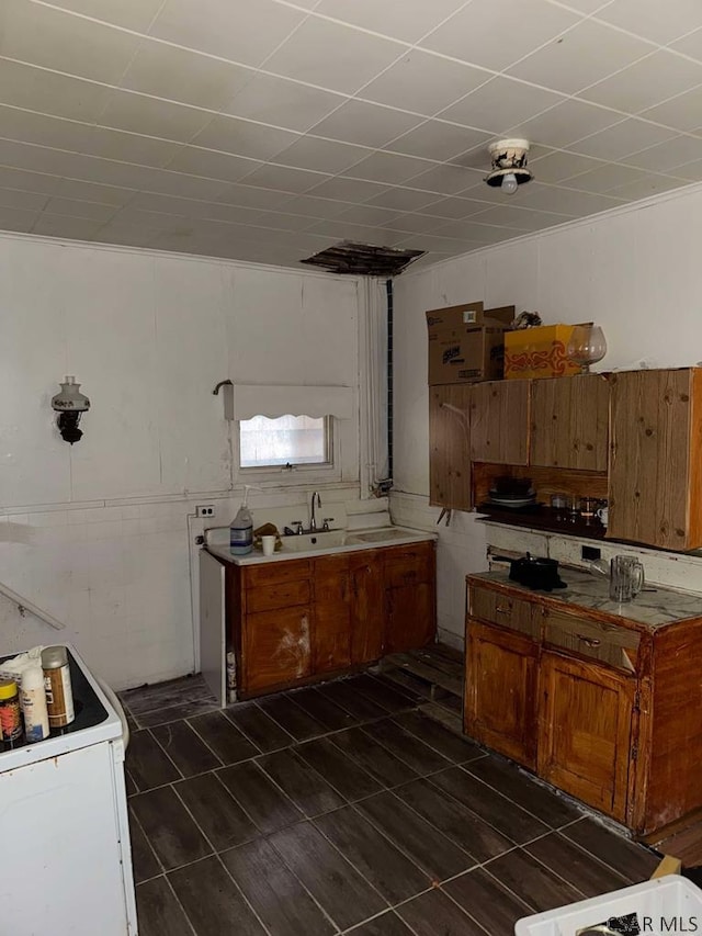 kitchen with a sink, white electric range, brown cabinets, and light countertops