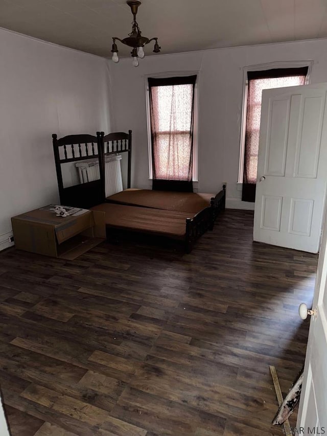 bedroom with a chandelier and dark wood finished floors