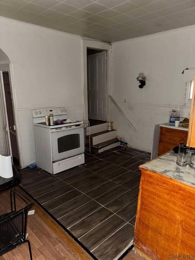 kitchen with arched walkways, dark wood finished floors, and white range with electric cooktop