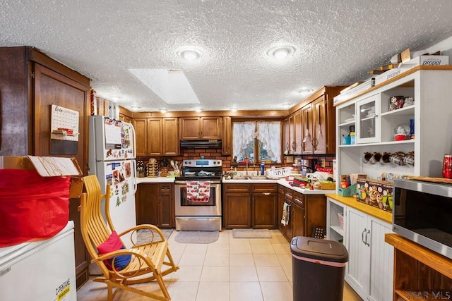 kitchen featuring stainless steel appliances, sink, light tile patterned floors, and a textured ceiling