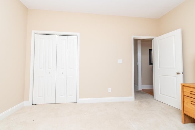 unfurnished bedroom with a closet and light colored carpet