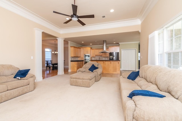 tiled living room featuring crown molding, decorative columns, ceiling fan with notable chandelier, and a healthy amount of sunlight