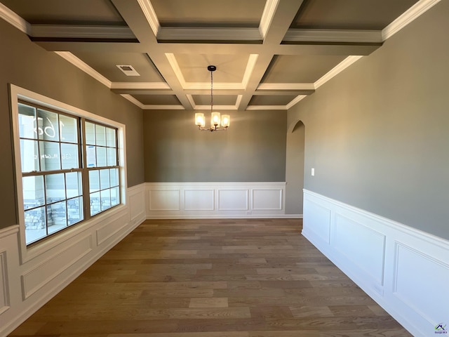 unfurnished dining area with a notable chandelier, crown molding, dark wood-type flooring, and coffered ceiling