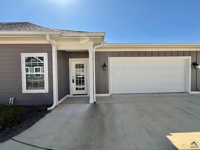 exterior space featuring a garage, concrete driveway, board and batten siding, and roof with shingles