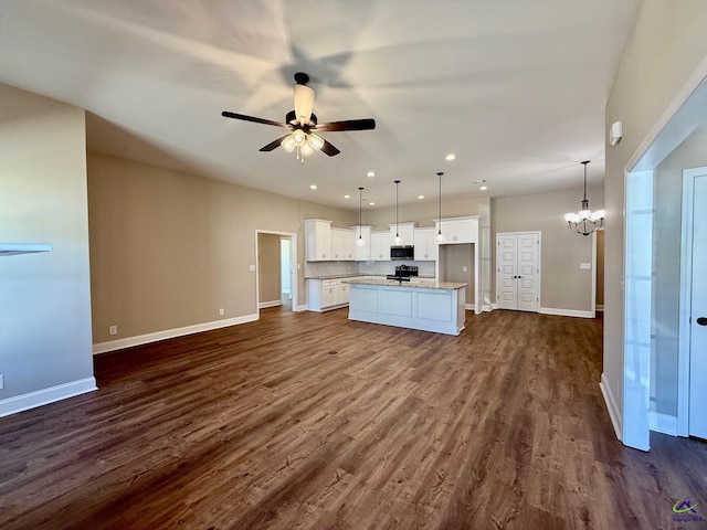 kitchen featuring dark wood-type flooring, open floor plan, white cabinets, baseboards, and ceiling fan with notable chandelier