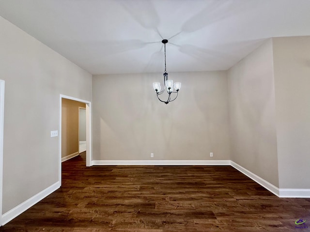 unfurnished dining area with dark wood-style floors, baseboards, and a notable chandelier