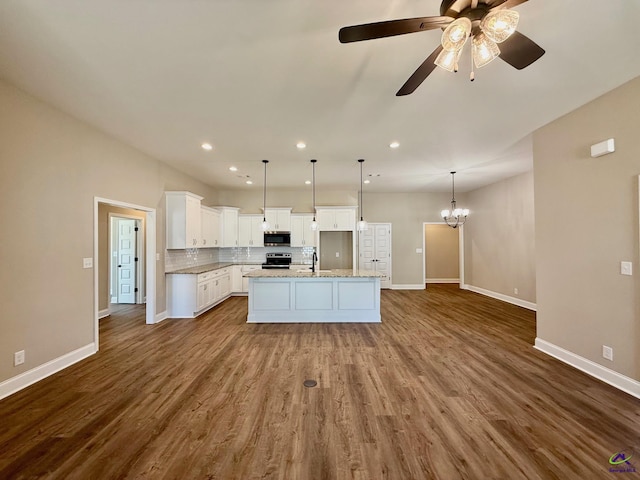 kitchen featuring a kitchen island with sink, dark wood-style flooring, a sink, open floor plan, and appliances with stainless steel finishes