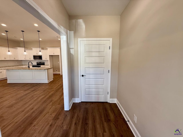 kitchen featuring dark wood-style flooring, stainless steel appliances, tasteful backsplash, white cabinetry, and baseboards