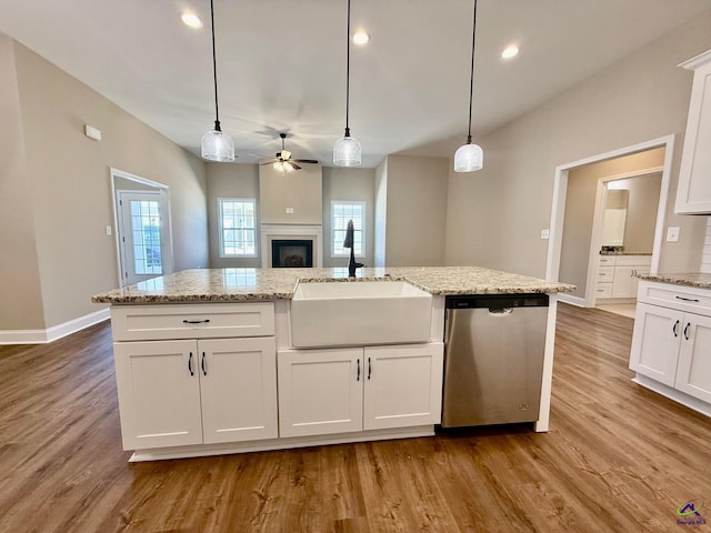 kitchen with wood finished floors, stainless steel dishwasher, a sink, and white cabinets