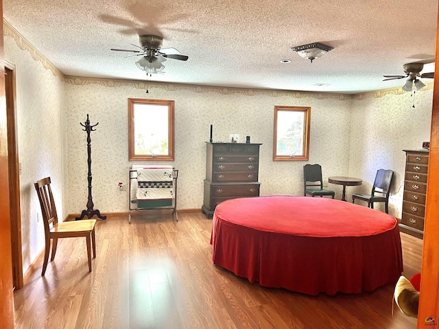 2382 Gallimore Mill Rd, Jeffersonville, GA 31044 - bedroom featuring wood finished floors, a textured ceiling, wallpapered walls, and ceiling fan