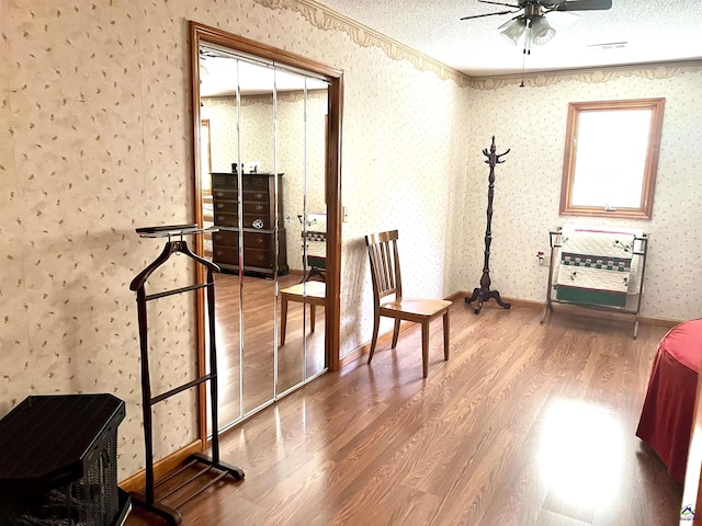 2382 Gallimore Mill Rd, Jeffersonville, GA 31044 - sitting room with wood finished floors, wallpapered walls, a ceiling fan, and a textured ceiling