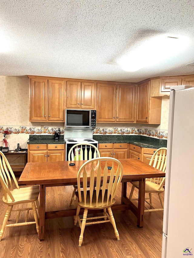 2382 Gallimore Mill Rd, Jeffersonville, GA 31044 - kitchen featuring freestanding refrigerator, electric range, light wood-style floors, dark countertops, and a textured ceiling