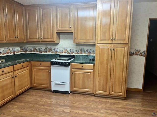 2382 Gallimore Mill Rd, Jeffersonville, GA 31044 - kitchen featuring white range, wallpapered walls, light wood-type flooring, and dark countertops