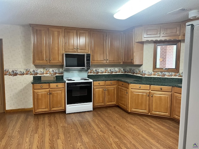 2382 Gallimore Mill Rd, Jeffersonville, GA 31044 - kitchen featuring black microwave, electric range, wood finished floors, wallpapered walls, and a textured ceiling
