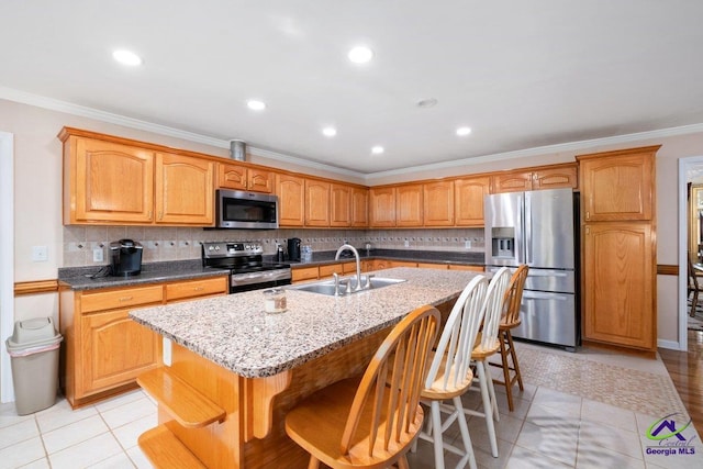 kitchen featuring sink, light tile patterned floors, an island with sink, a kitchen bar, and stainless steel appliances