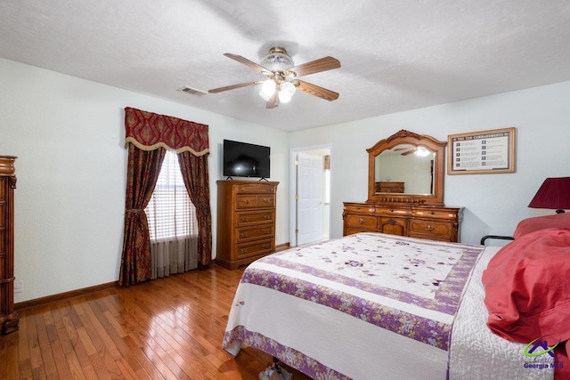 bedroom with a textured ceiling, light hardwood / wood-style flooring, and ceiling fan