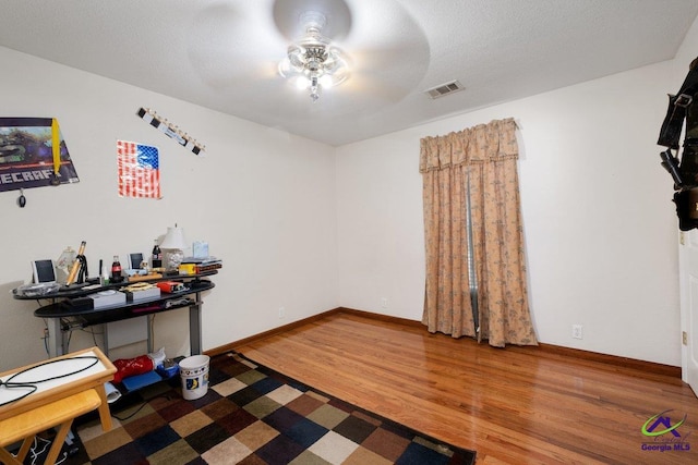 interior space featuring ceiling fan, hardwood / wood-style floors, and a textured ceiling