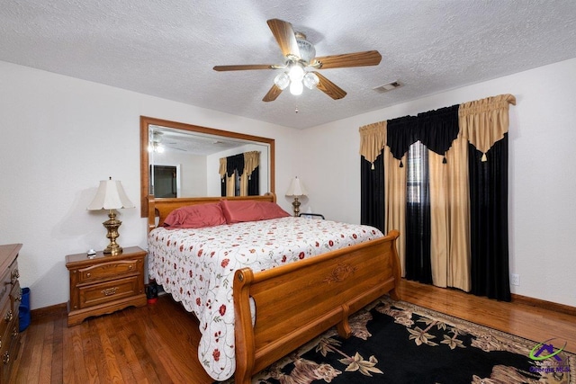 bedroom featuring ceiling fan, dark hardwood / wood-style floors, and a textured ceiling