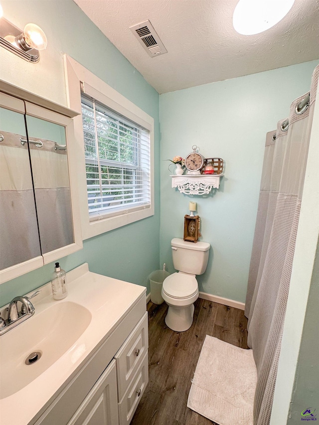 bathroom featuring oversized vanity, toilet, a textured ceiling, and wood-type flooring