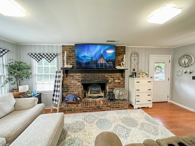 living room featuring brick wall, light hardwood / wood-style floors, a fireplace, and a wealth of natural light