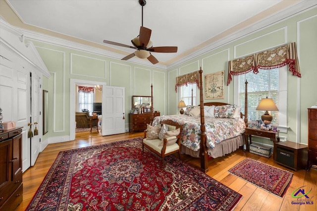 bedroom with ceiling fan, light wood-type flooring, ornamental molding, and multiple windows