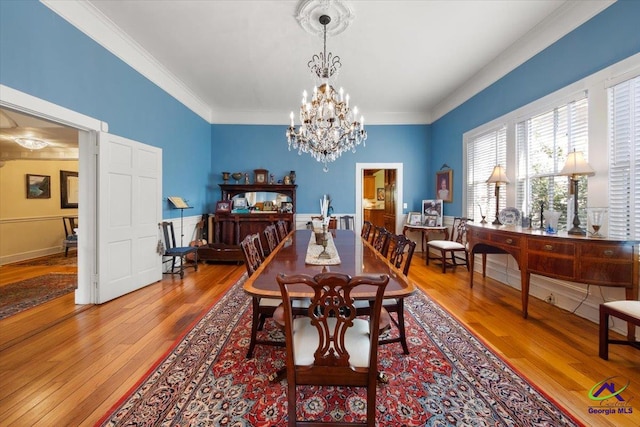 dining space featuring ornamental molding, a chandelier, and light hardwood / wood-style flooring