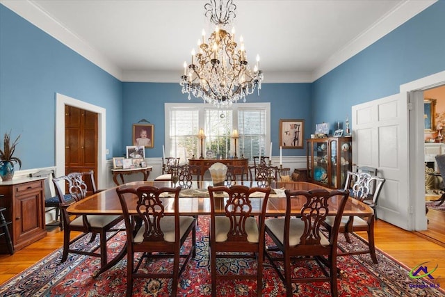 dining room with light hardwood / wood-style flooring, ornamental molding, and a notable chandelier